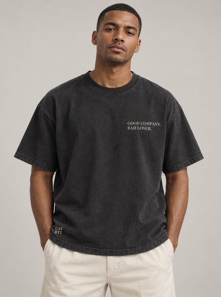 Studio render: a man in a washed charcoal T-shirt with the words Good company. Bad loser. on the chest.